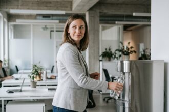 Employée remplissant sa bouteille à une fontaine à eau moderne dans un open space contemporain